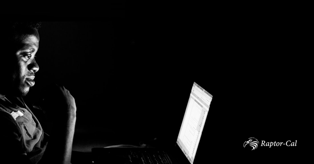 A black and white image of a man working at a laptop. Raptor Cal is open on the laptop's screen